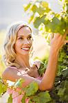Smiling woman touching grapevine