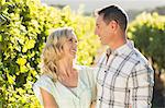 Smiling couple embracing and standing next to grapevine