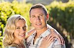 Portrait of smiling couple embracing next to grapevine