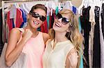Friends wearing sunglasses in front of clothes racks