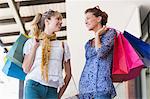 Beautiful women holding shopping bags looking at each other
