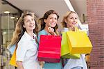 Beautiful women holding shopping bags looking away