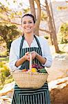 Cheerful woman holding basket of vegetables