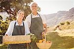 Smiling farmer couple holding a vegetable basket