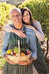 Smiling couple holding basket with fruits