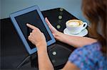 Woman having coffee and using her tablet