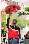 Man in wheelchair with Spinal Meningitis shopping for flowers at a farmer's market