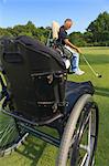 Man with a spinal cord injury in an adaptive cart at golf putting green