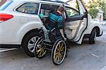 Trendy man with a spinal cord injury in wheelchair getting into a taxi cab