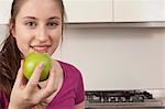 teenage girl eating an apple in kitchen