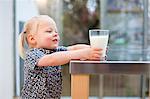 Toddler girl holding glass of milk