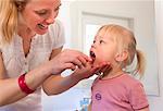 Mother brushing toddler daughter's teeth