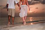 Couple walking hand-in-hand on beach