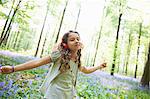 Girl listening to headphones in forest