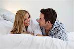 Couple in bathrobes laying on bed