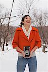 Teenage girl holding vintage camera in snow