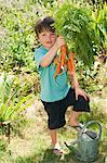 Boy holding bunch of homegrown carrots, portrait