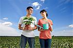 Couple in field with watering can and plant