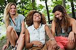 Three young women laughing in forest