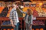 Young woman pushing apple into man's face