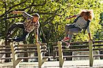 Couple leaping over park benches