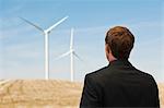 Young man watching wind turbines