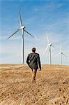 Man walking in front of wind turbines