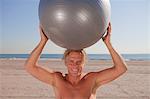 Man on beach holding exercise ball