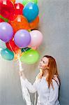 Young woman with bunch of balloons