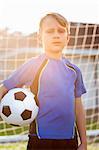 Portrait of boy football player holding football in front of goal
