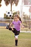 Girl kicking football on practice pitch