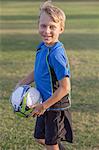 Portrait of boy football player holding football on practice pitch