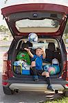 Boy football player sitting in car boot throwing and catching football