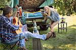 Young woman photographing boyfriend playing acoustic guitar whilst camping