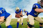 Team of teenage American football players practicing on playing field