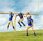 Team of teenage and adult American footballers practicing next to field goal