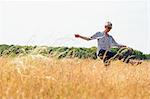 Playful senior woman dancing in sunny rural field