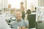 Portrait smiling fashion designer drinking coffee in office