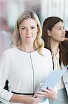 Portrait confident businesswoman with folder and digital tablet