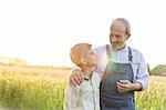 Grandfather farmer and grandson hugging in rural wheat field