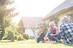 Grandparents and grandson eating harvested strawberries in sunny yard
