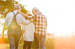 Affectionate grandparents and grandson walking along sunny rural wheat field