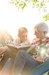 Grandmother reading to grandson in sunny hammock