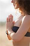 Close up serene woman in bikini meditating with hands at heart center