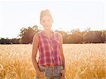 A young woman standing in a field of tall ripe corn.