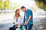 Smiling couple with a scooter outdoors