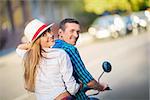 Smiling couple on a scooter outdoors