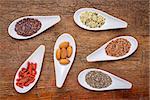 superfood grain, seed, berry, and nuts  abstract - top view of spoon bowls against rustic wood