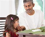 Indian family dining at home. Candid photo of India people eating rice with hands. Parent feeding child.