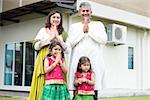 Indian family folded hands representing traditional Indian greeting on Diwali, festival of lights, outside their new home.